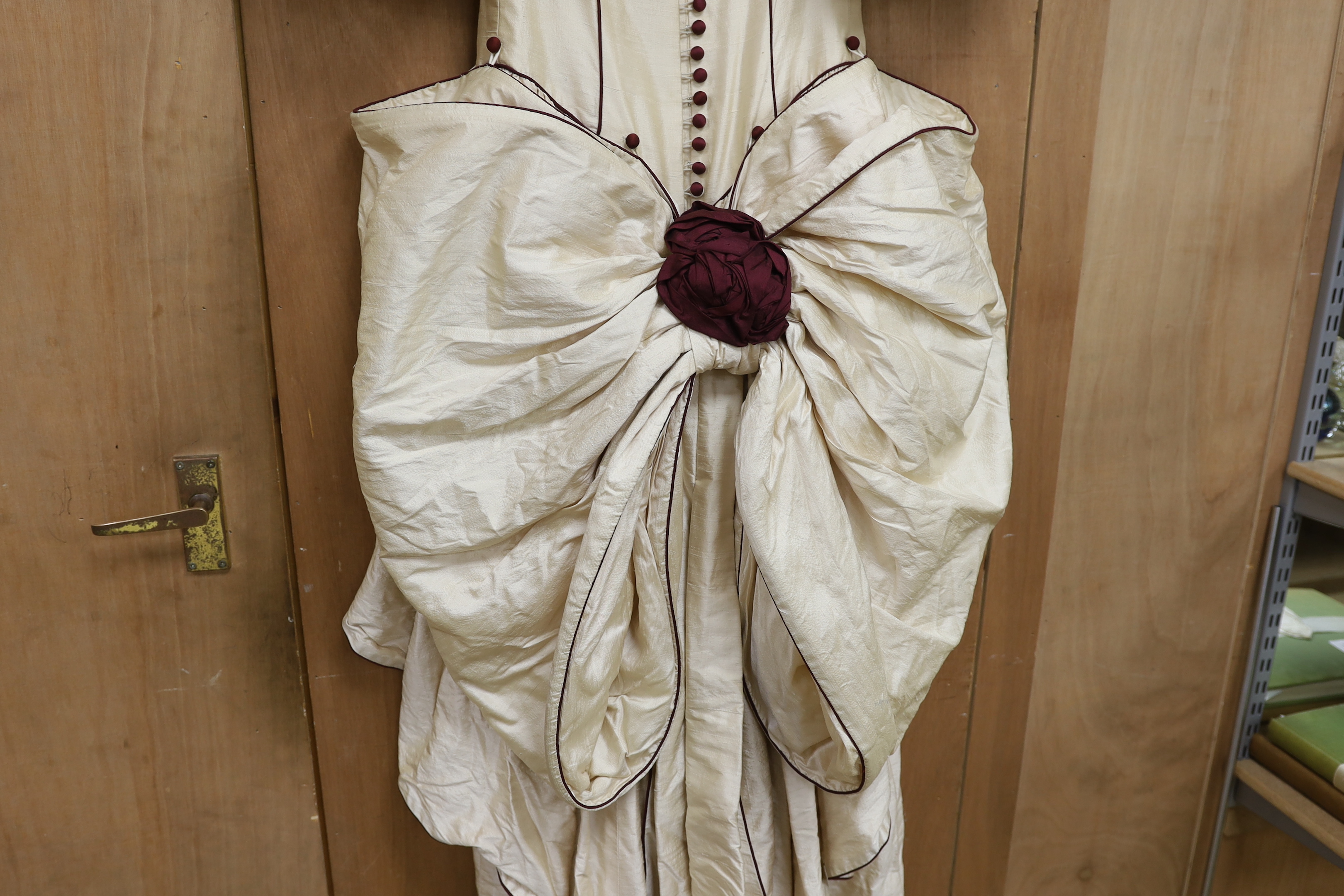 A late 20th century cream silk and burgundy trimmed gown, with bustle, possibly operatic or theatrical